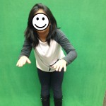 Child poses for green screen image. Face covered for privacy.