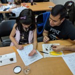 Youth and adult participant comparing bone findings to bone chart.