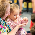 An adult and child inspect an object closely.